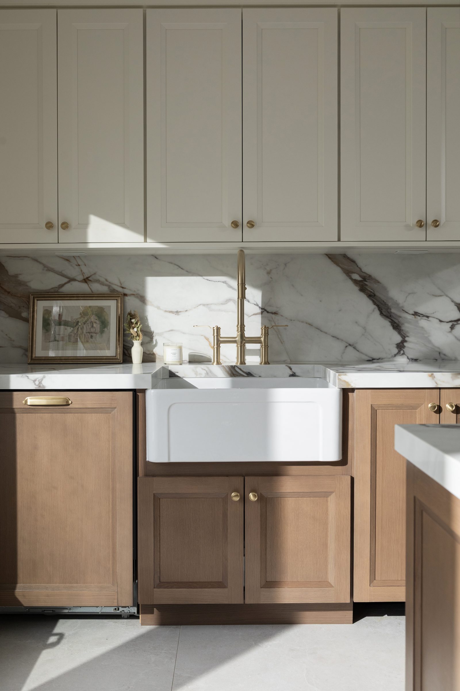 Rift cut white oak cabinetry in the Ale finish, with a farmhouse sink, marble backsplash and brass bridge faucet